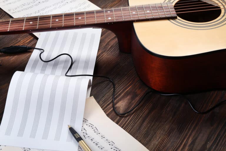 Guitar and music sheets on wooden background